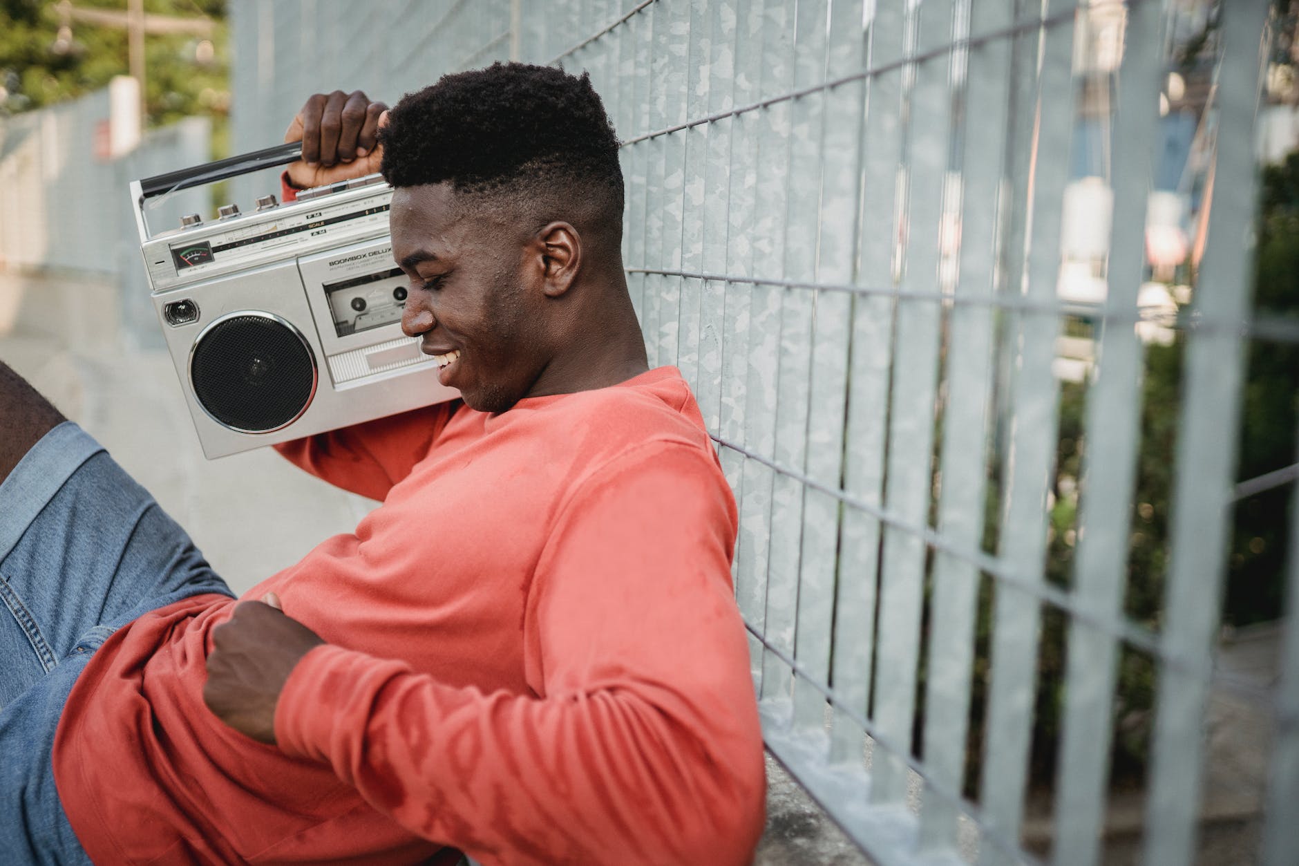 smiling black man enjoying music from old tape recorder outdoors