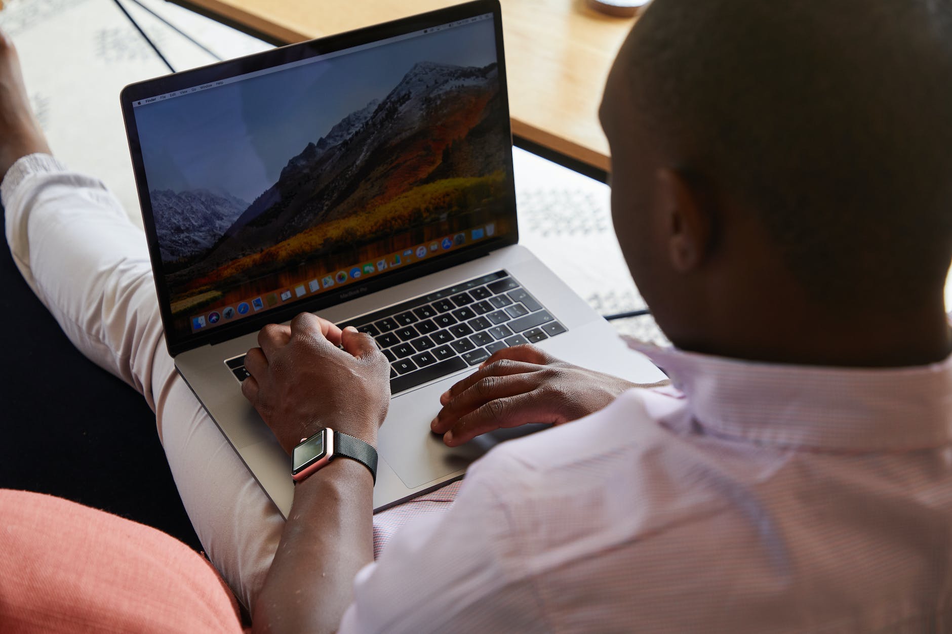 black man with smart watch using touchpad of laptop