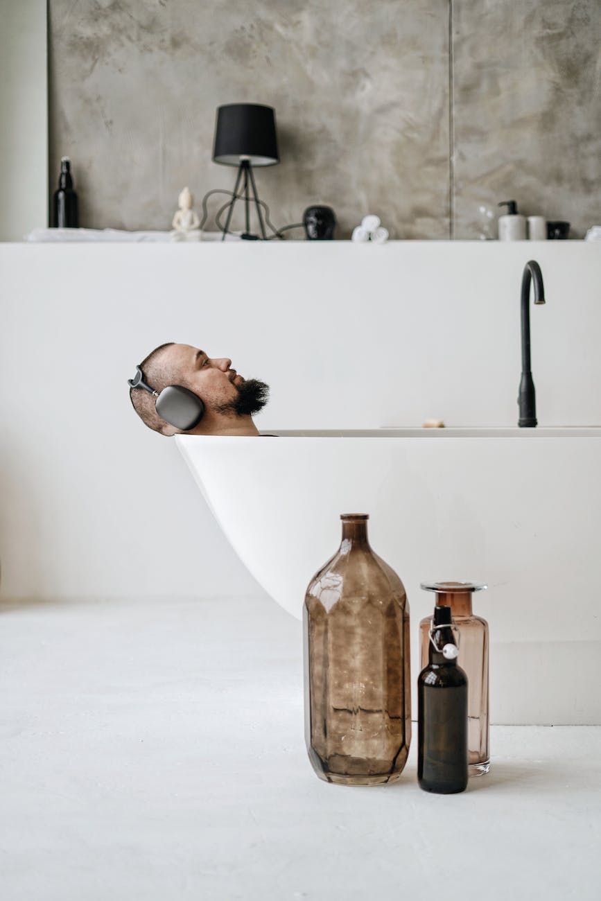 man with headphones lying inside a bathtub