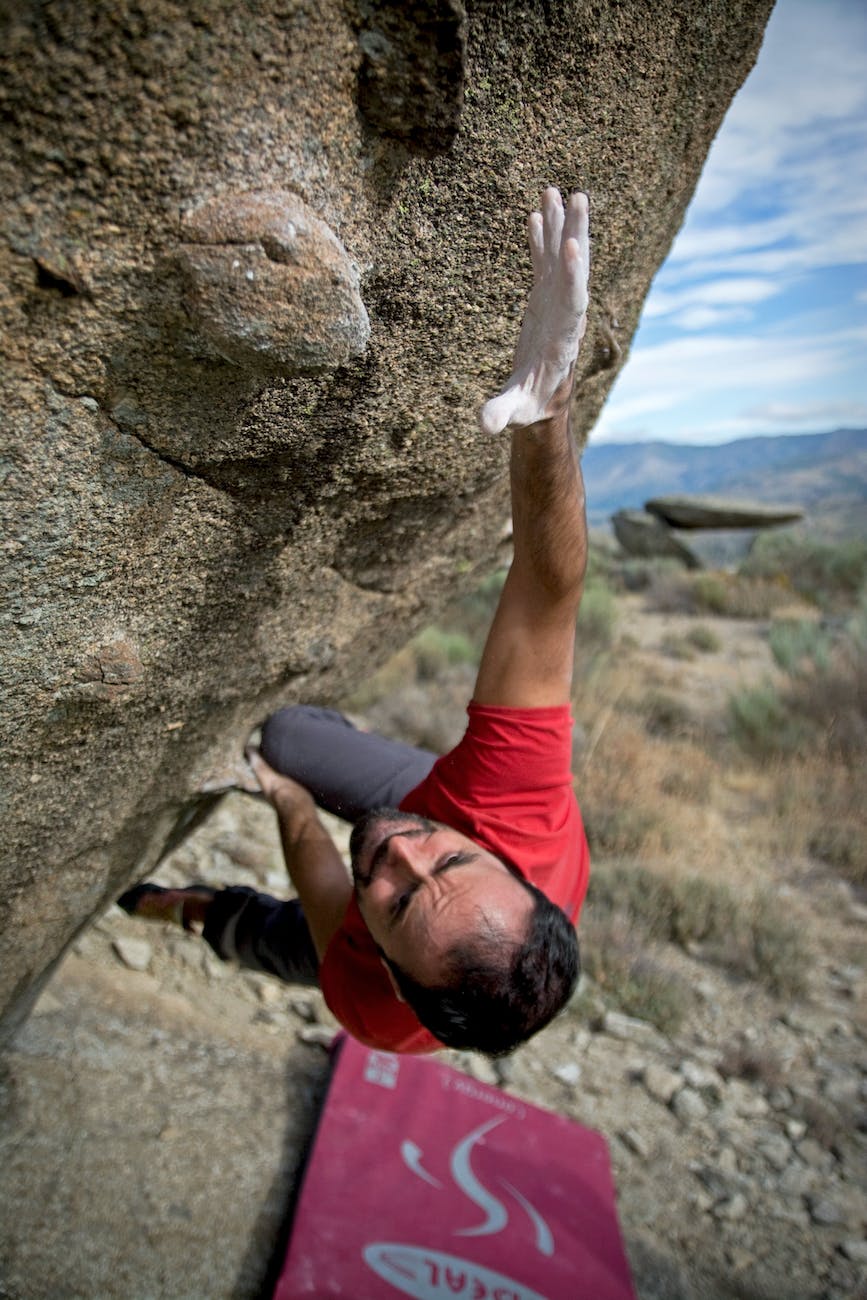 man climbing on gray concrete peak at daytime