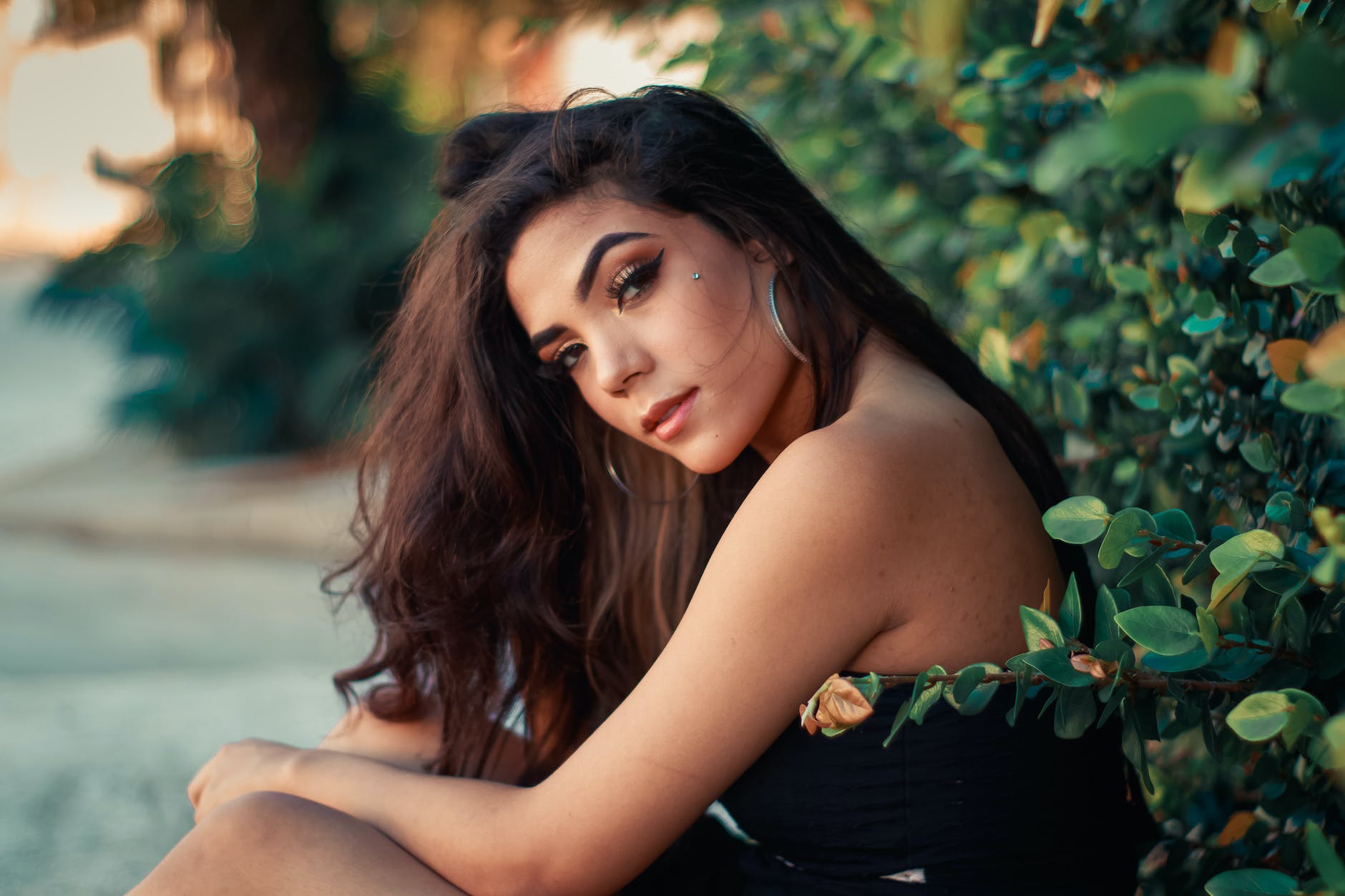 beautiful brunette woman sitting in front of leaves