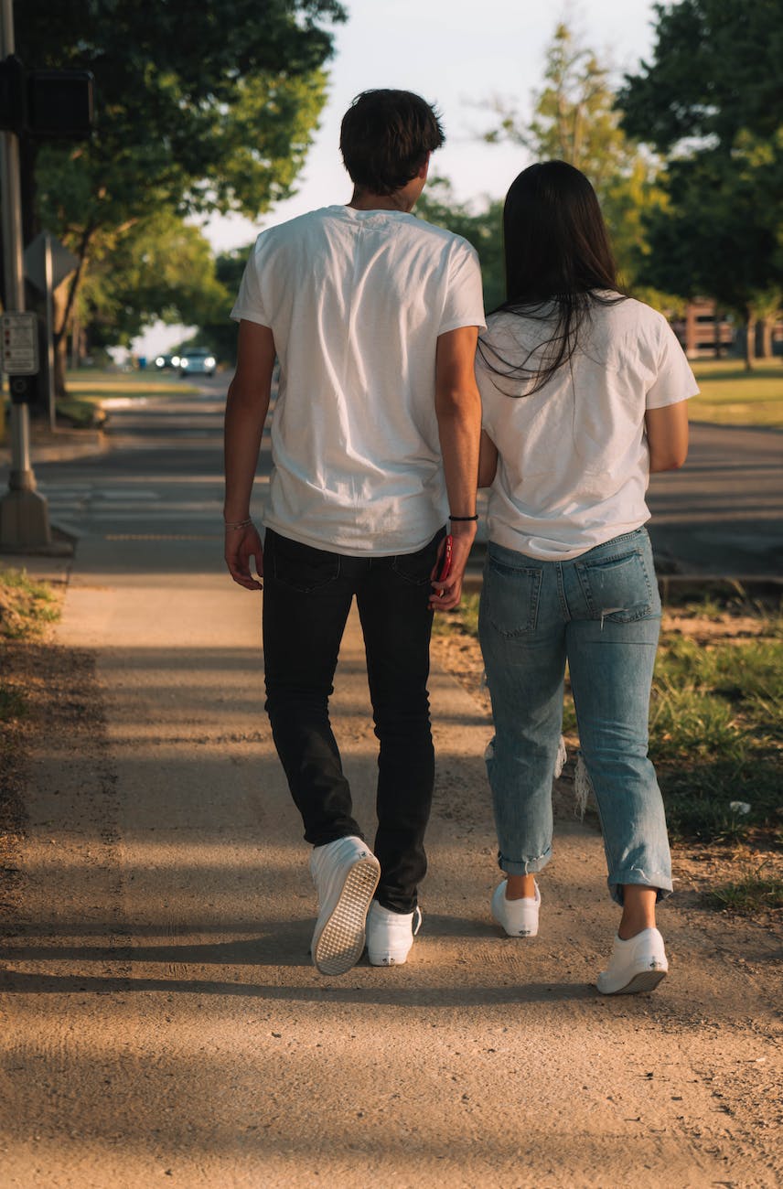 young couple in white t shirts and trainers walking on suburban street