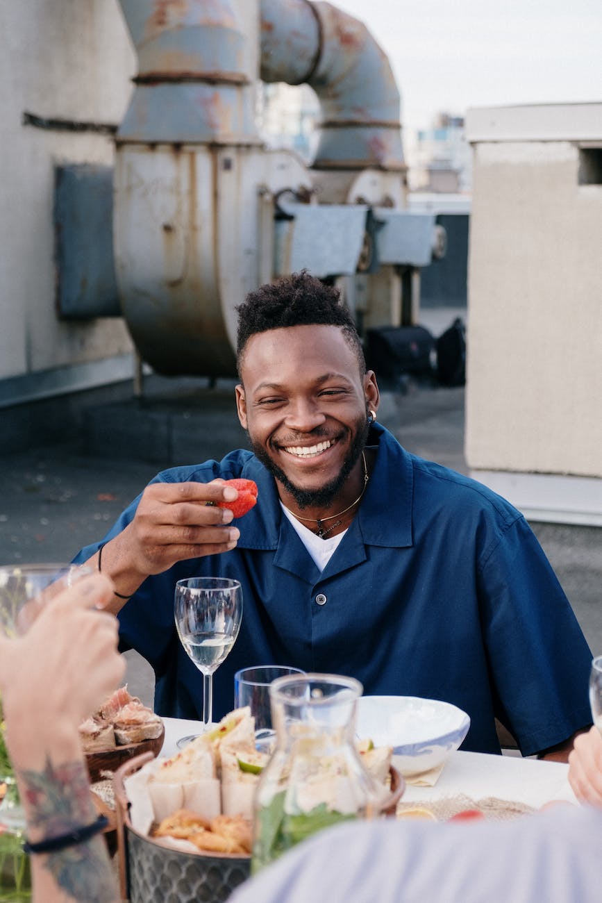 man in blue dress shirt holding clear drinking glass