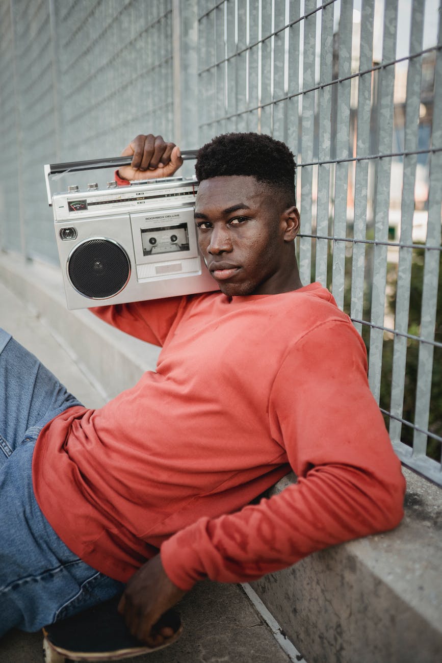 black skateboarder listening to music on vintage cassette recorder outdoors