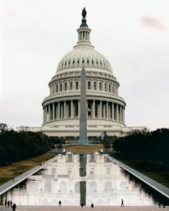 washington state capitol facade reflecting in pond under white sky