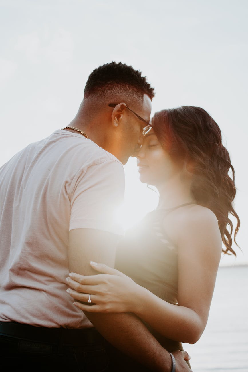 man wearing white shirt kissing woman in her nose