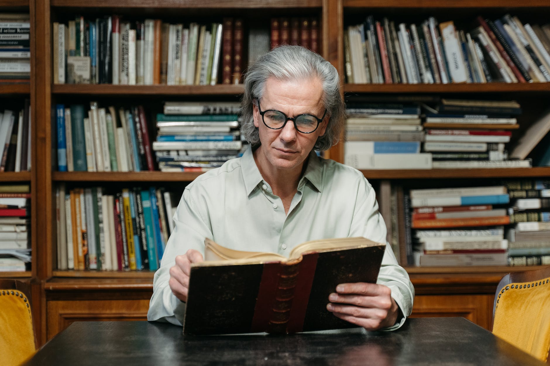 an elderly man reading a book at a library