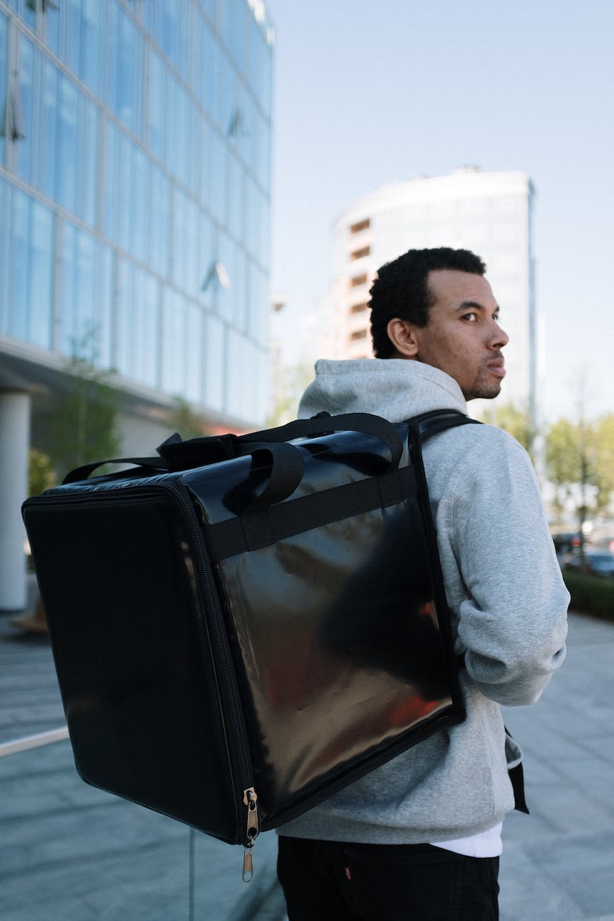 man in gray hoodie carrying black leather bag