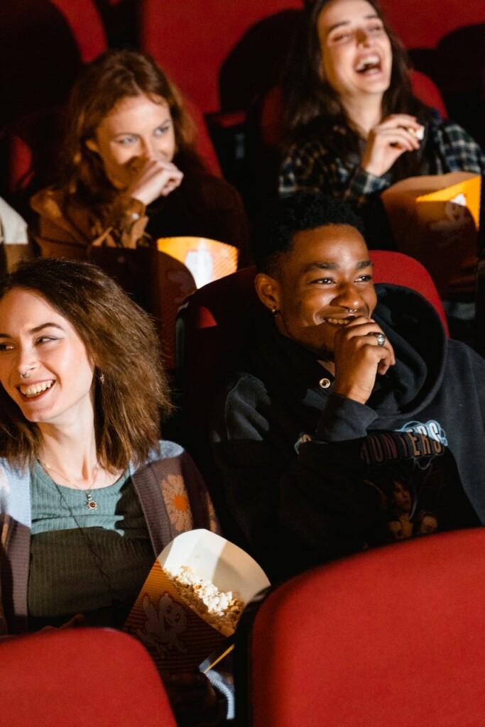 people watching movie while holding buckets of popcorn