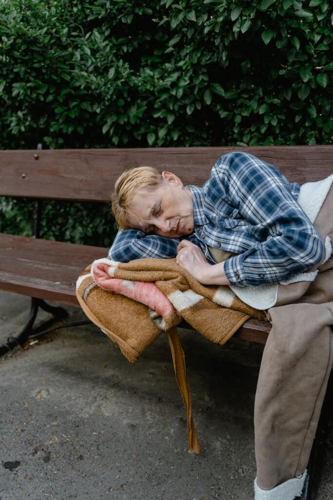 person sleeping on a wooden bench