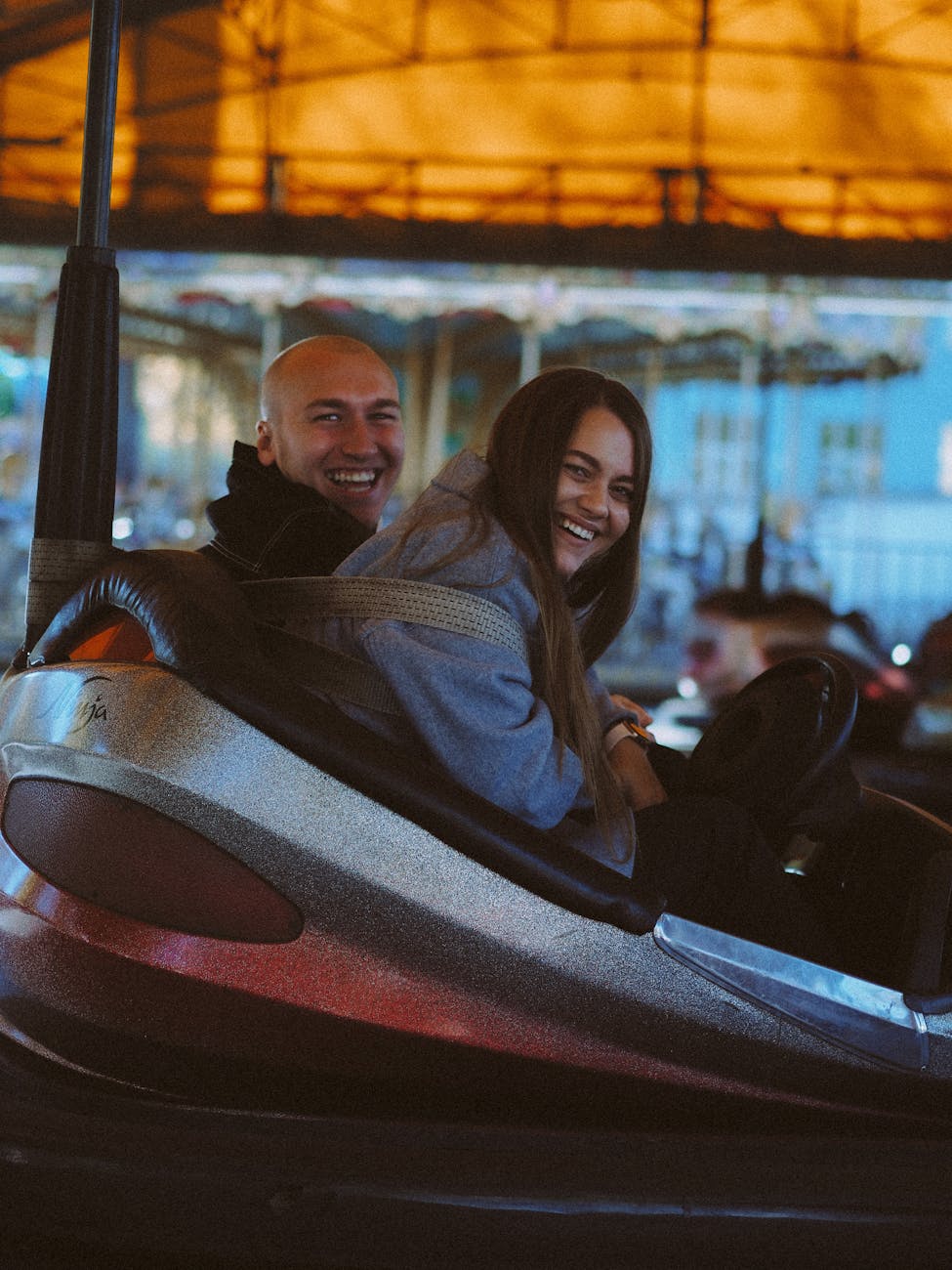 sweet couple riding on a bump car while smiling at the camera