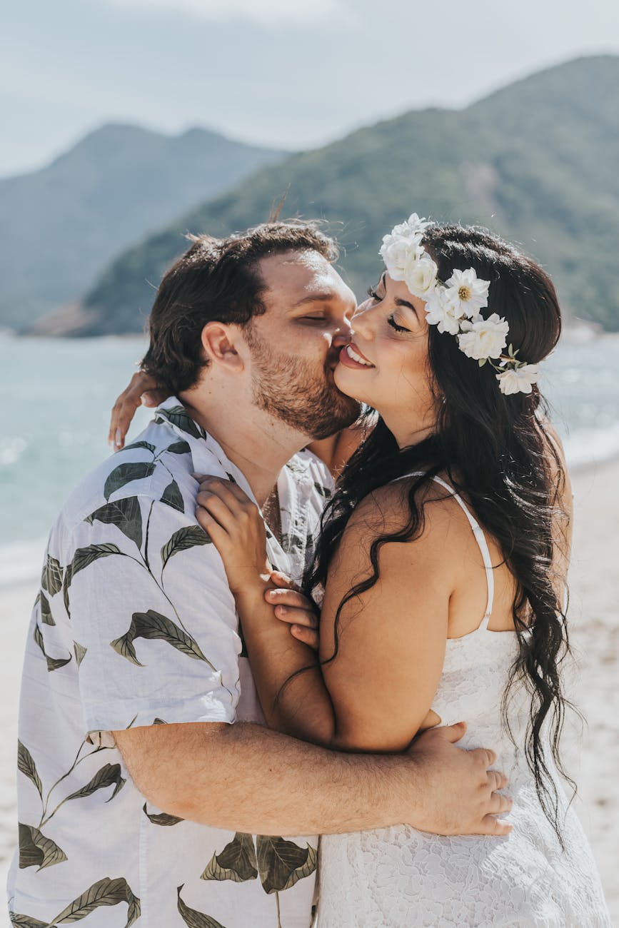 a couple standing on a beach and kissing