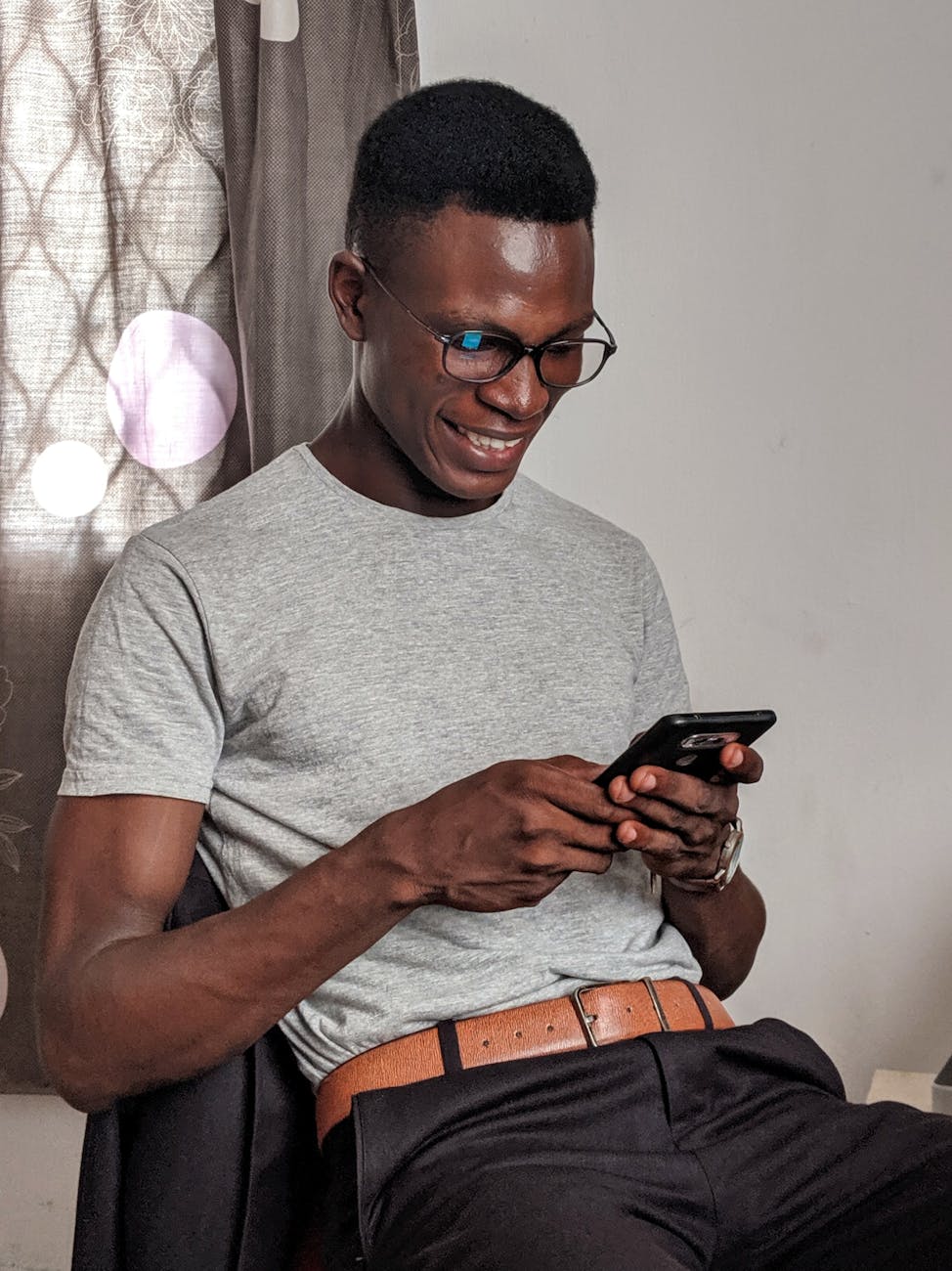 man wearing gray crew neck shirt holding black smartphone