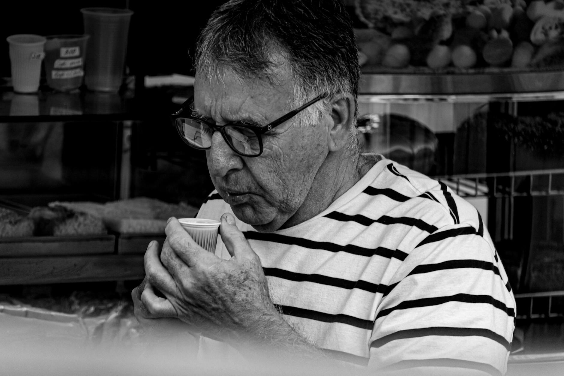 black and white photo of an elderly man holding a small plastic cup