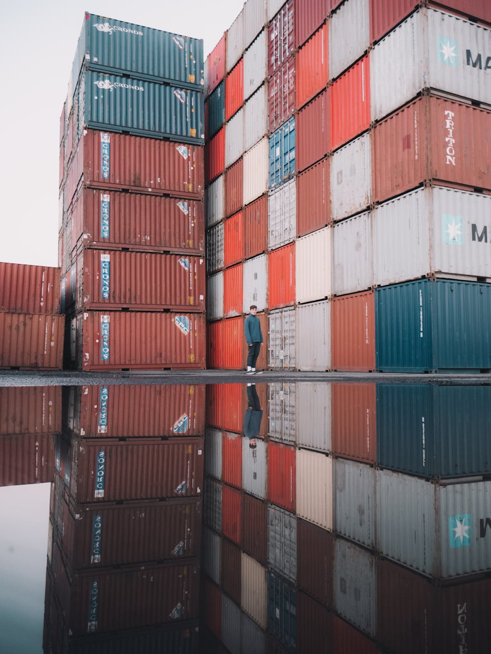 man standing near a stack of cargo containers