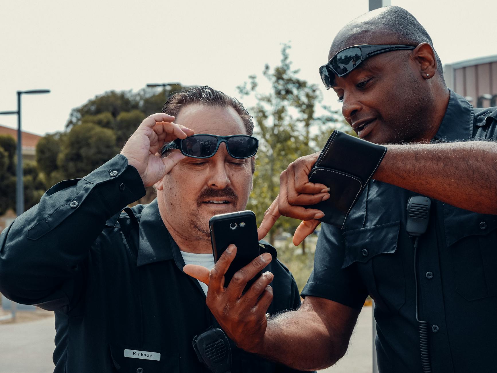 man in black sunglasses holding black smartphone