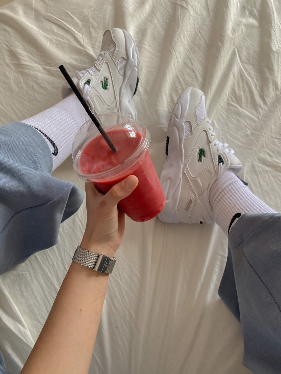 a person wearing white shoes while holding a smoothie