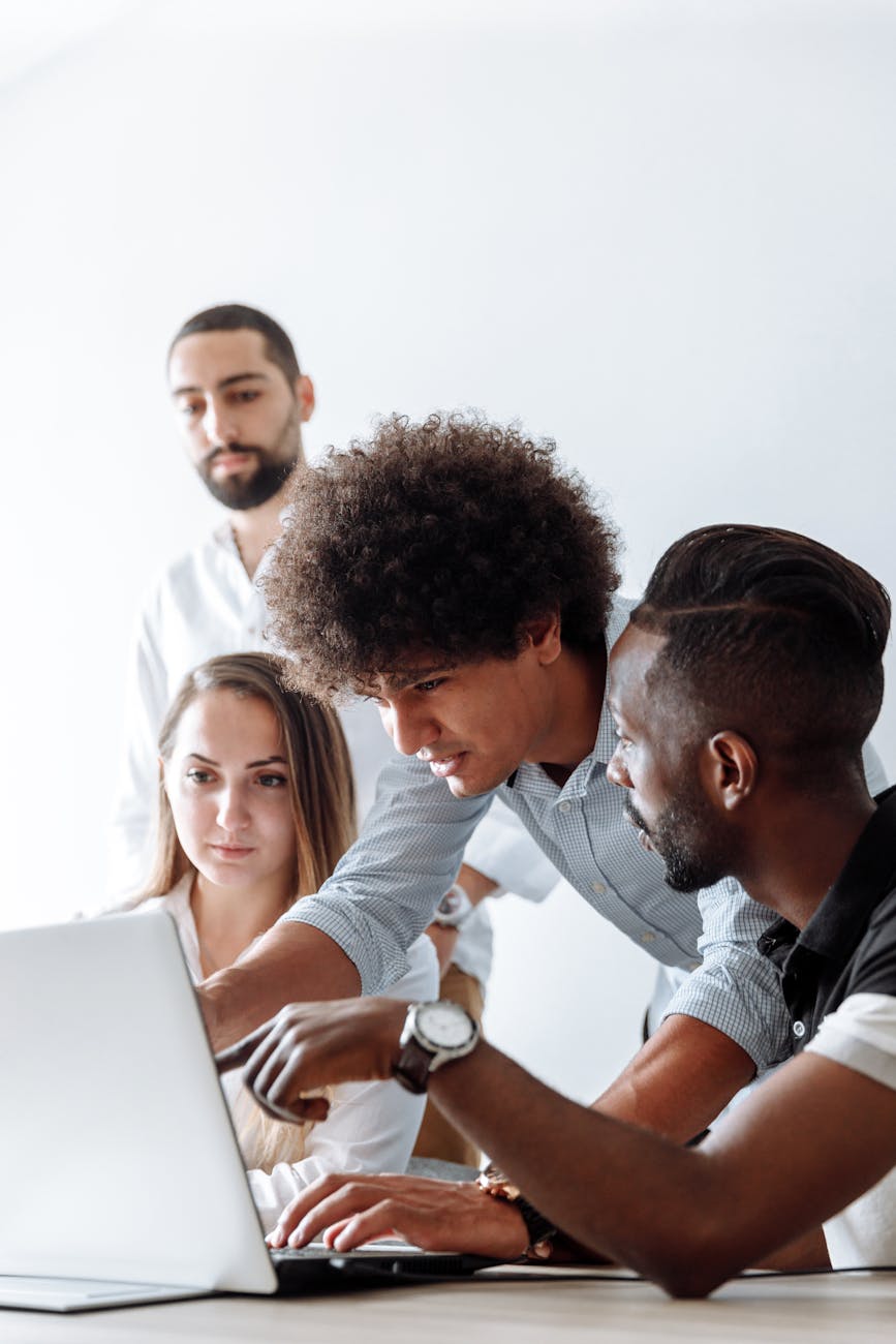 a man talking to his colleagues while showing something at the laptop