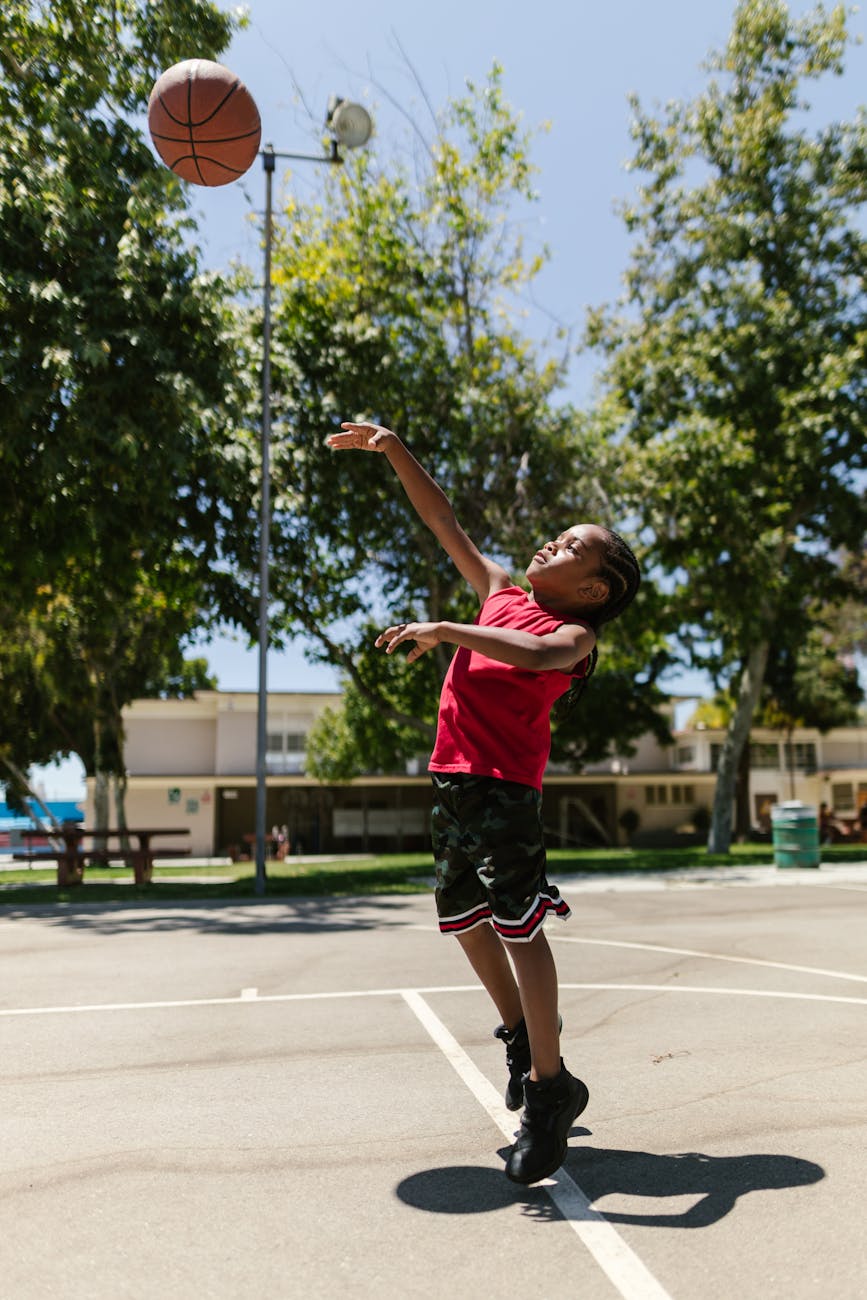 boy in black shorts and red sleeveless shirt playing basketball