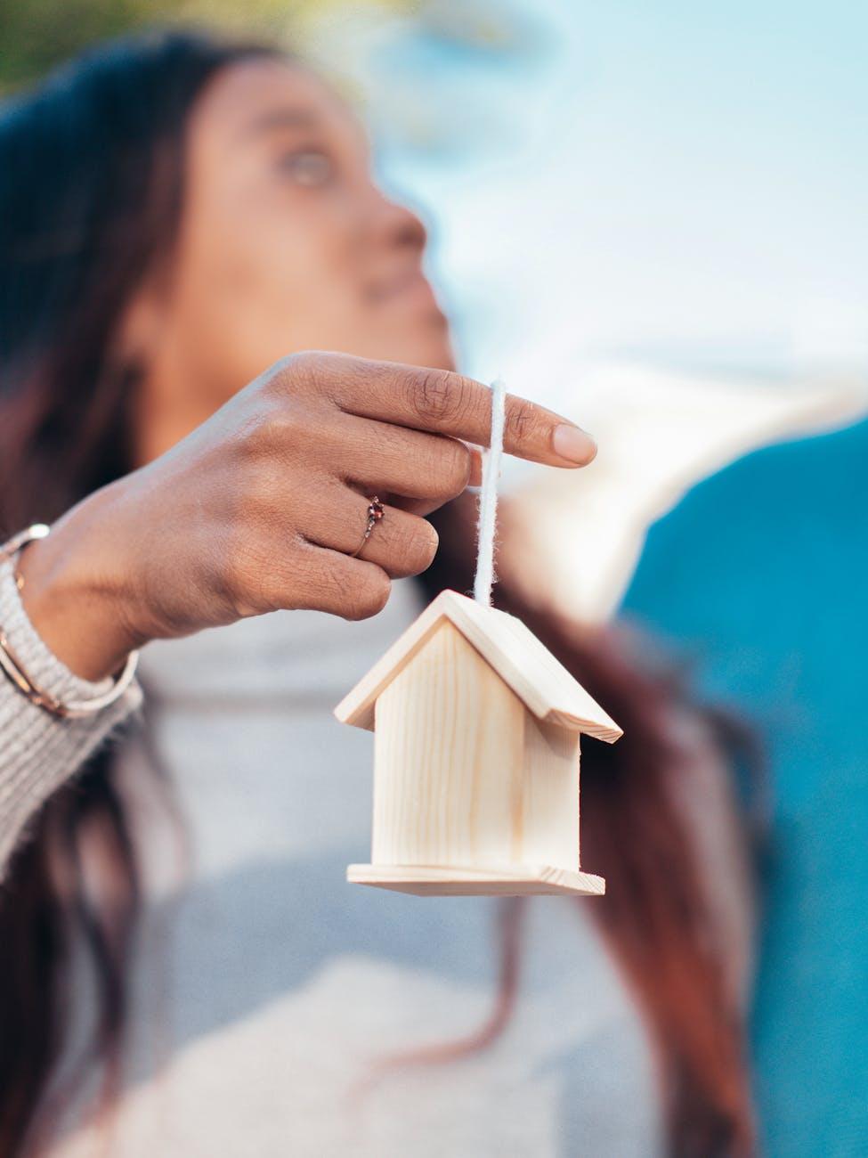 woman holding miniature wooden house