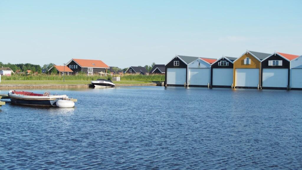 A serene view of colorful boathouses along the shore with boats docked on a calm summer day.