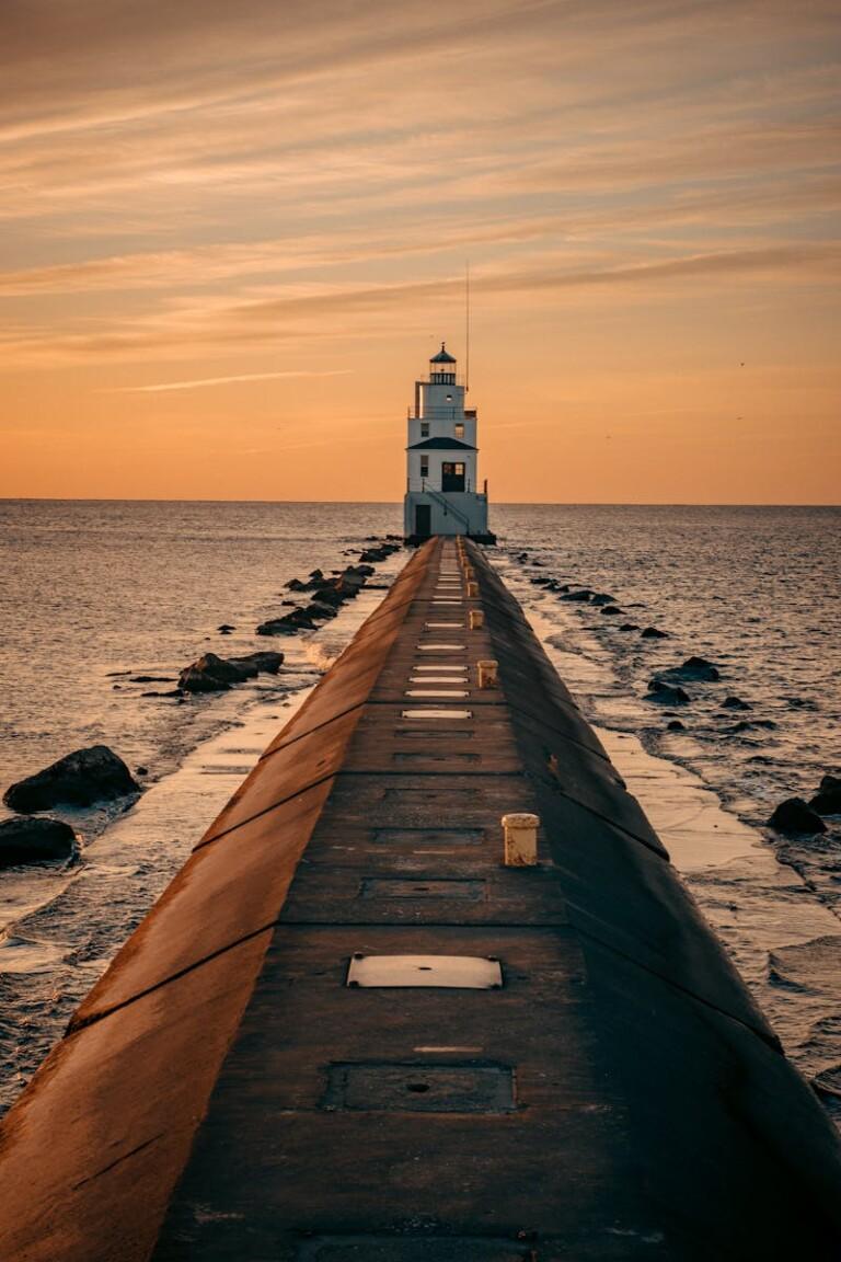 Stunning sunset view of the Manitowoc Breakwater Lighthouse, WI, capturing the tranquil ocean and warm skies.