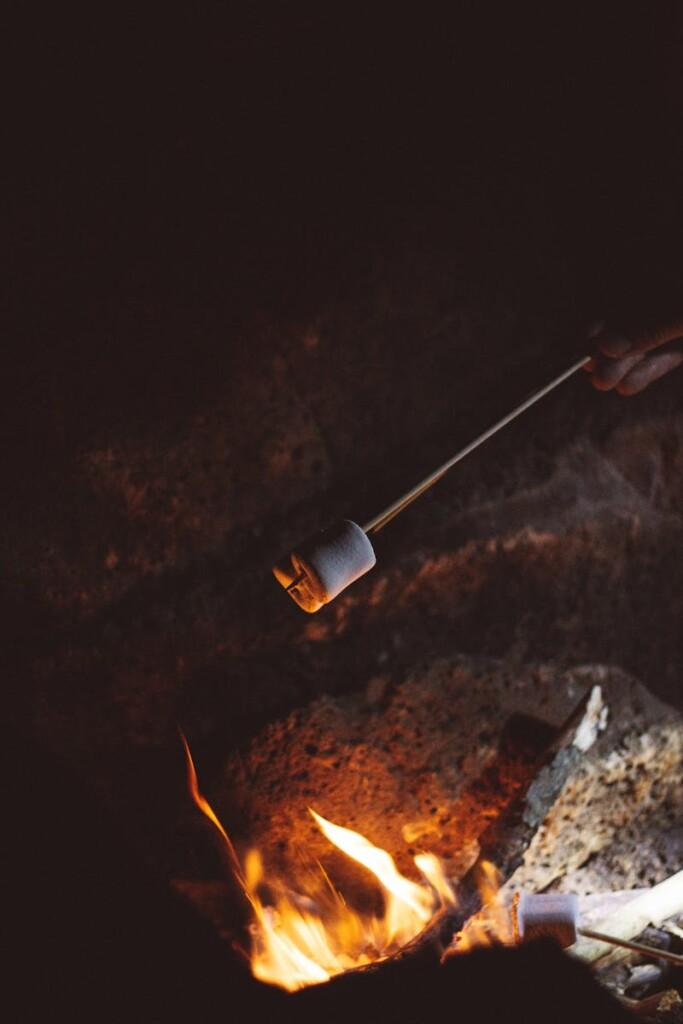 A cozy night scene capturing a marshmallow being roasted over a glowing campfire.