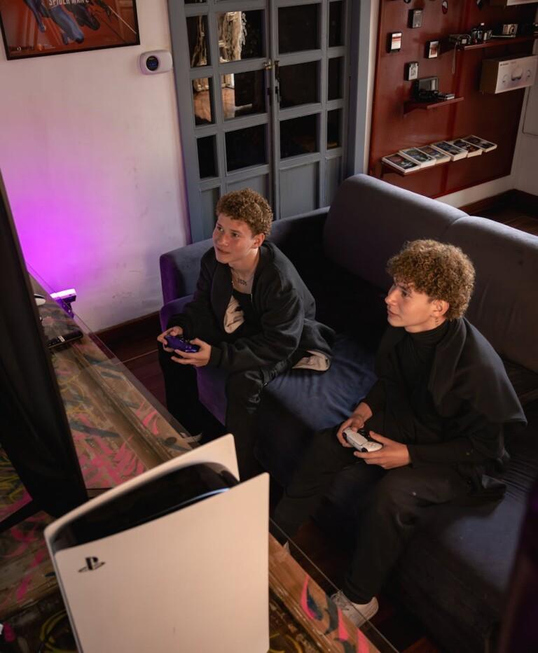 Two teenage boys enjoy gaming on a console indoors in Cuenca, Ecuador, creating fun and social moments.