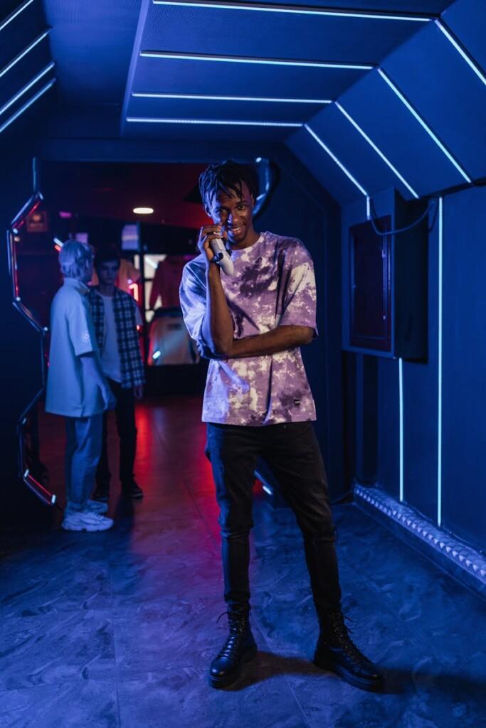 Young black man smiling and gaming in a futuristic neon arcade setting.