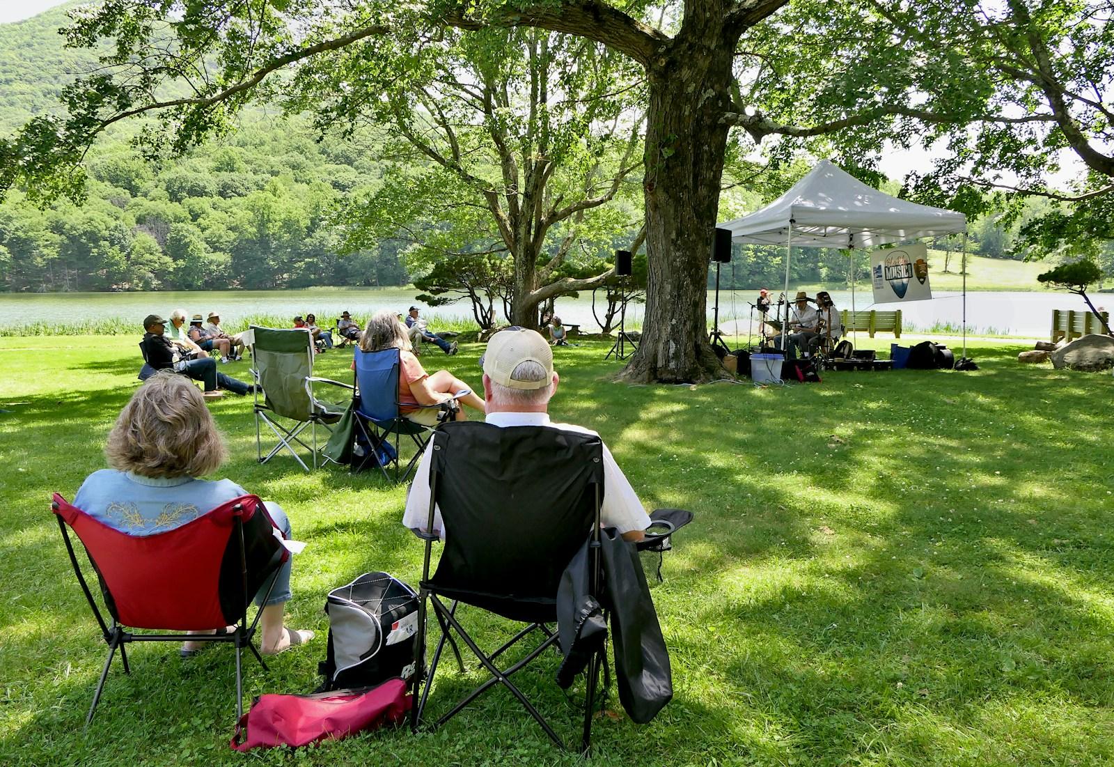 a group of people sitting in lawn chairs under a tree