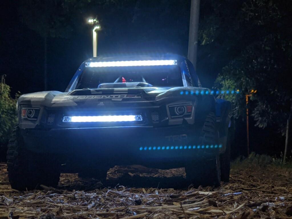 a truck with lights on driving through a forest