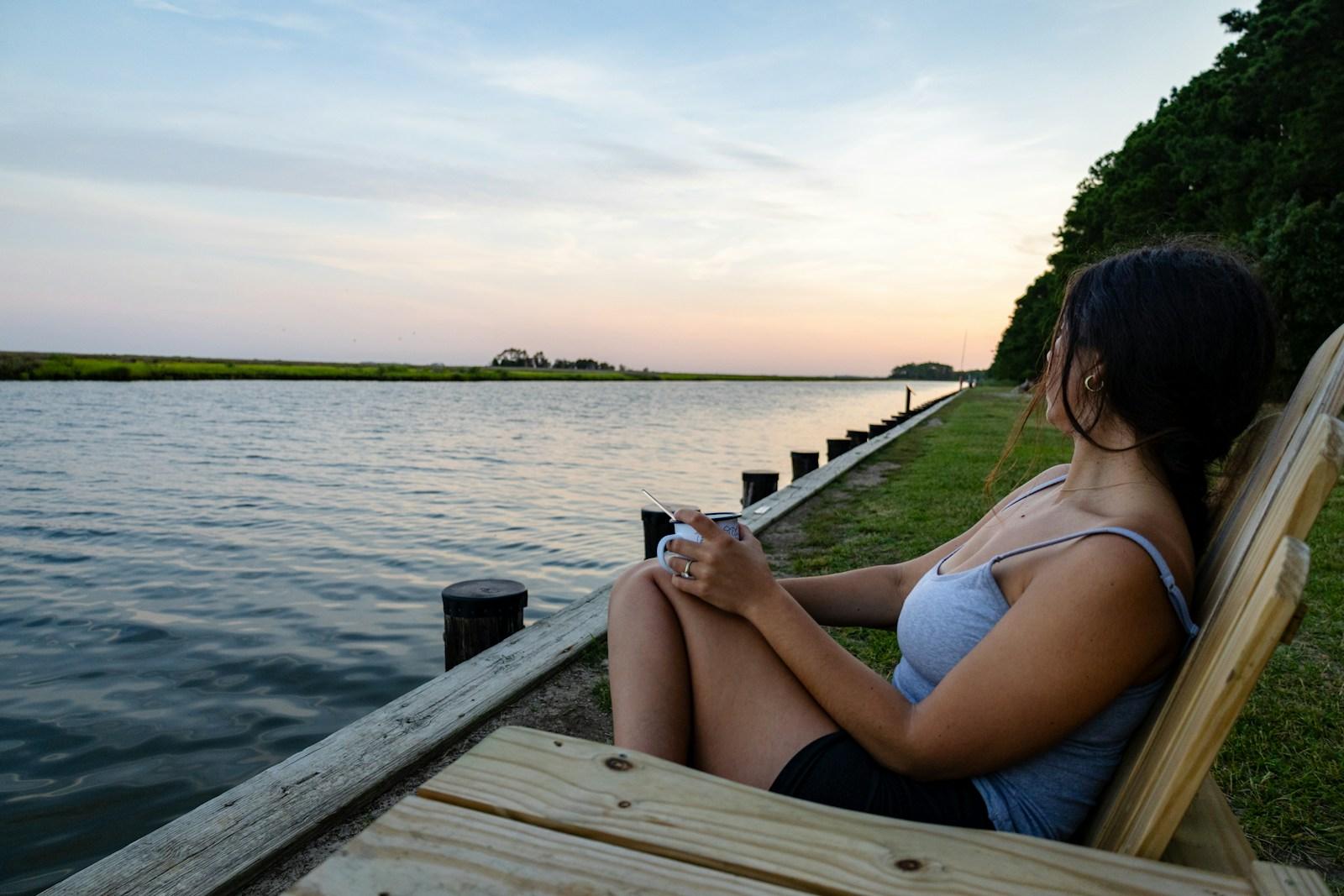 A woman sitting in a chair on the edge of a body of water