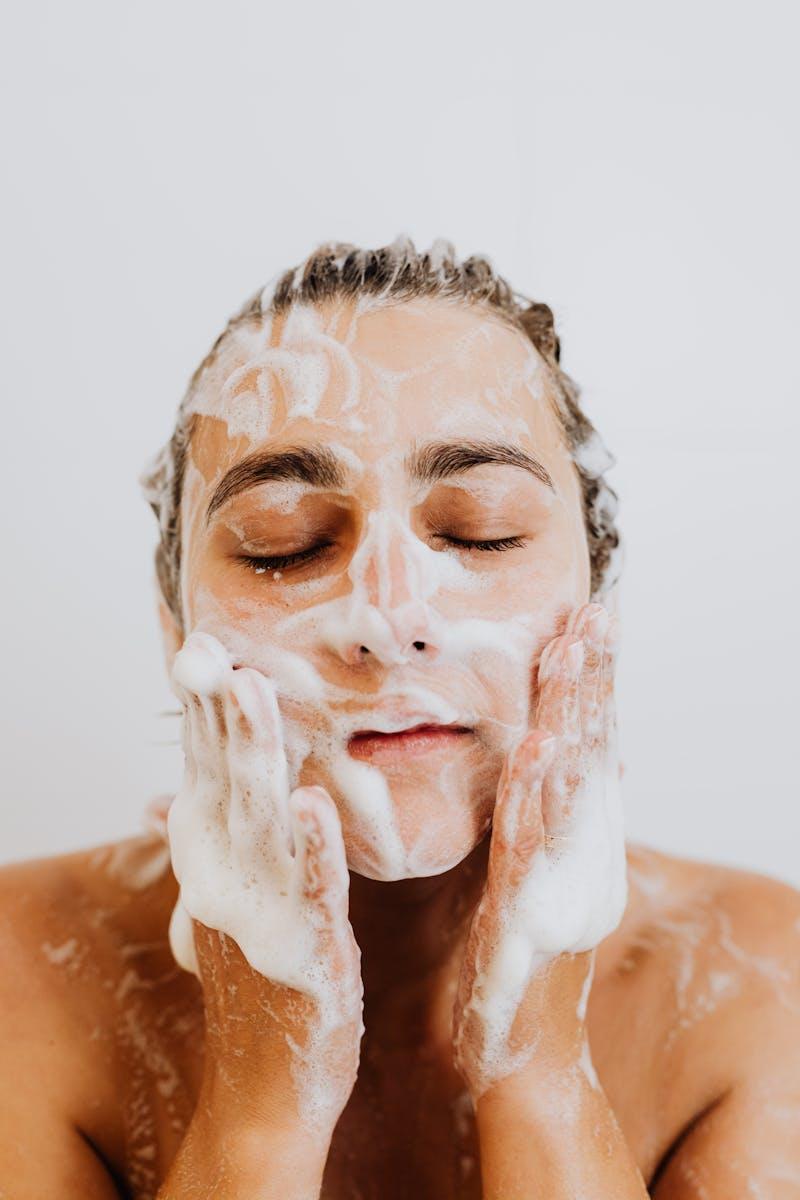 Woman washing her face with foam cleanser, focusing on skincare and hygiene.